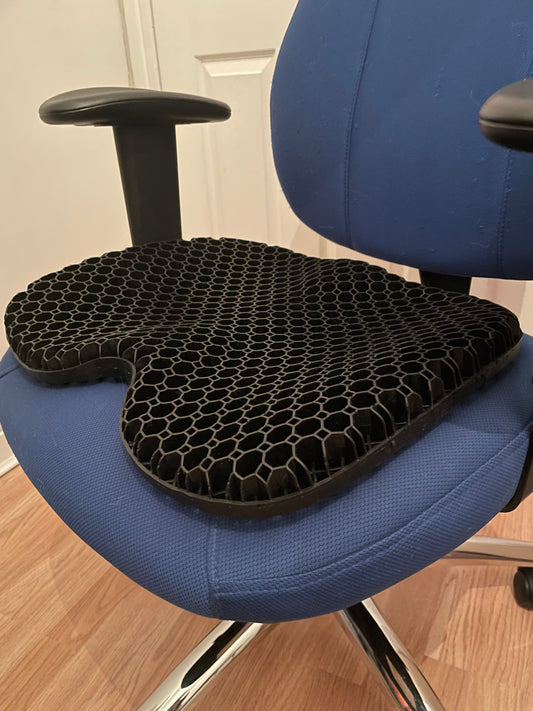 Ergonomic SpineSaver seat cushion placed on a computer chair, designed for improved comfort, posture support, and back pain relief.